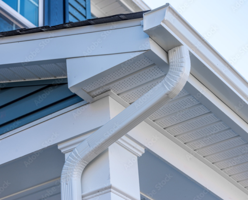 Colonial white gutter guard system, fascia, drip edge, soffit providing ventilation to the attic, with pacific blue vinyl horizontal siding at a luxury American single family home neighborhood USA
