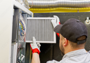 HVAC service technician changing dirty air filter in the central ventilation system. Change filter in rotary heat exchanger recuperator. Air duct ventilation system maintenance for clean air.