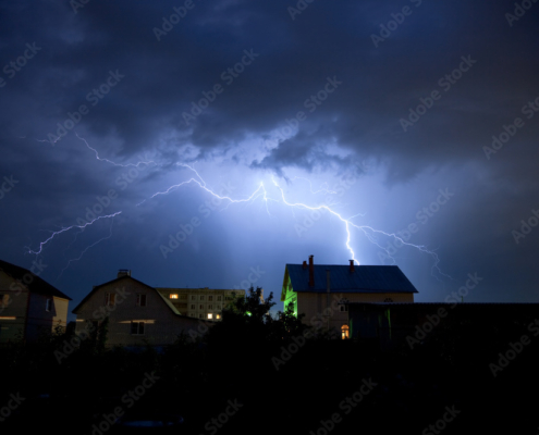 Lightning in the cloudy sky over village