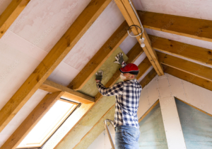 Man installing thermal roof insulation layer - using mineral wool panels. Attic renovation and insulation concept