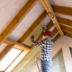 Man installing thermal roof insulation layer  - using mineral wool panels. Attic renovation and insulation concept