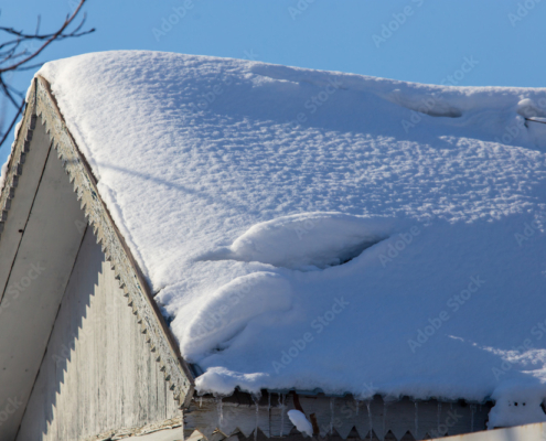 Snow on the roof of the house in winter