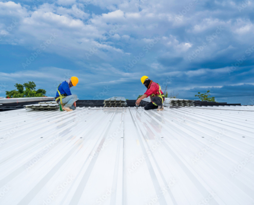 Teamwork of Roofer working at new roof under construction. Safety body construction, Fall arrestor device for worker with hooks for safety body harness on the roof structure. building