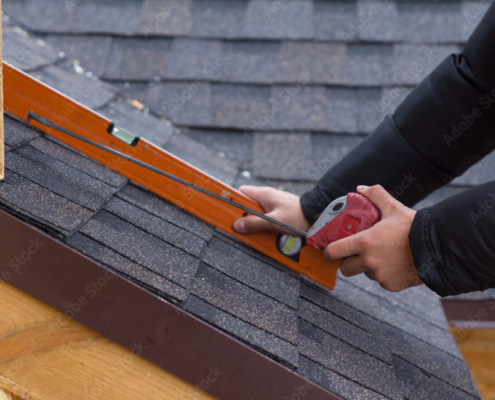 Roofer holding a tape measure and level