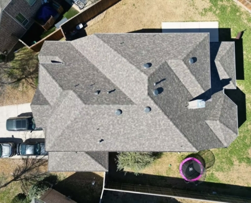 Top-down aerial of a large gray shingle roof with turbine vents on a suburban home