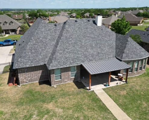 Aerial of a home with a new gray shingle roof and a standing-seam metal patio cover