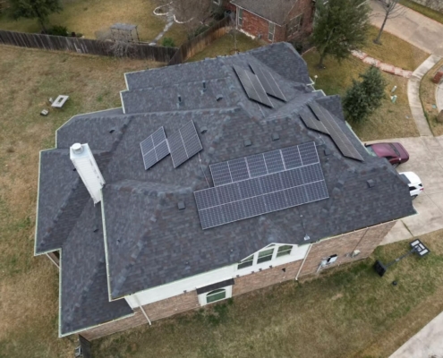 Aerial view of a charcoal shingle roof with rooftop solar panels on a two-story North Texas brick home