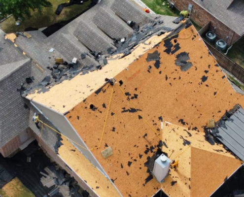 Aerial view of a suburban home mid-reroof with old shingles torn off and bare wood decking exposed