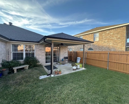 Backyard patio of a brick home with a newly finished hip roof at dusk in North Texas