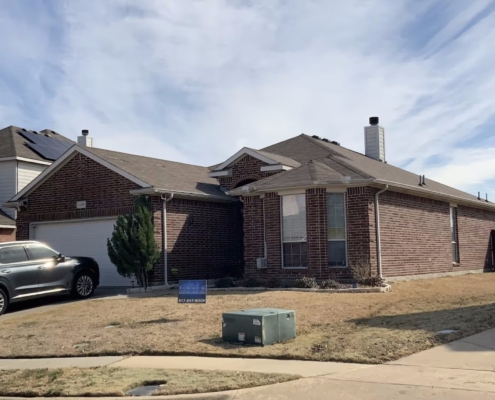 Brick home with a completed brown shingle roof and a Davis Roofing sign in the winter yard