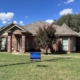Single-story brick home with a finished brown shingle roof and a Davis Roofing yard sign out front