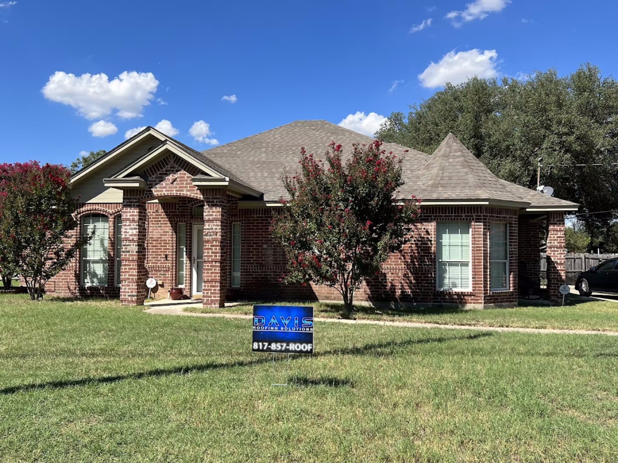 Brick Dallas-Fort Worth home with a freshly maintained shingle roof and Davis Roofing Solutions yard sign