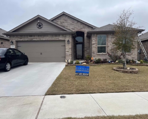Brick home with a freshly installed shingle roof and a work ladder set against the eave.