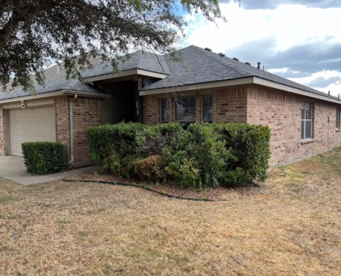 Brick ranch home with a freshly installed dark shingle roof and clean gutter line