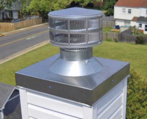 Close-up of a new galvanized chimney cap and chase cover above a roofline