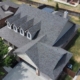Aerial of a finished shingle roof with four dormers on a large brick home