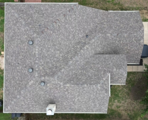 Overhead drone view of a completed light gray shingle roof with three turbine vents