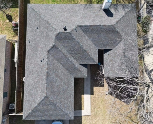Overhead drone view of a completed multi-gable roof with new gray-brown shingles