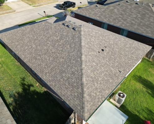 Drone view of a finished tan asphalt shingle roof with box vents on a single-story home.