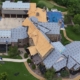 Aerial of a large estate mid roof replacement with crews and exposed decking across several sections