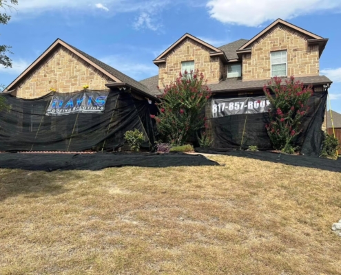 Stone-and-brick home fitted with fall-protection netting during a roof replacement