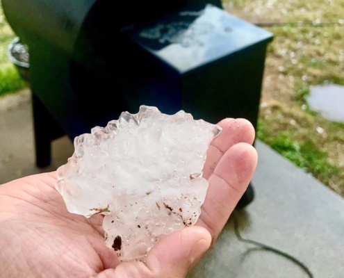 Close-up of a large jagged hailstone held in a hand after a North Texas storm