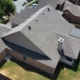 Aerial of a multi-gable home with a freshly installed tan-and-gray shingle roof