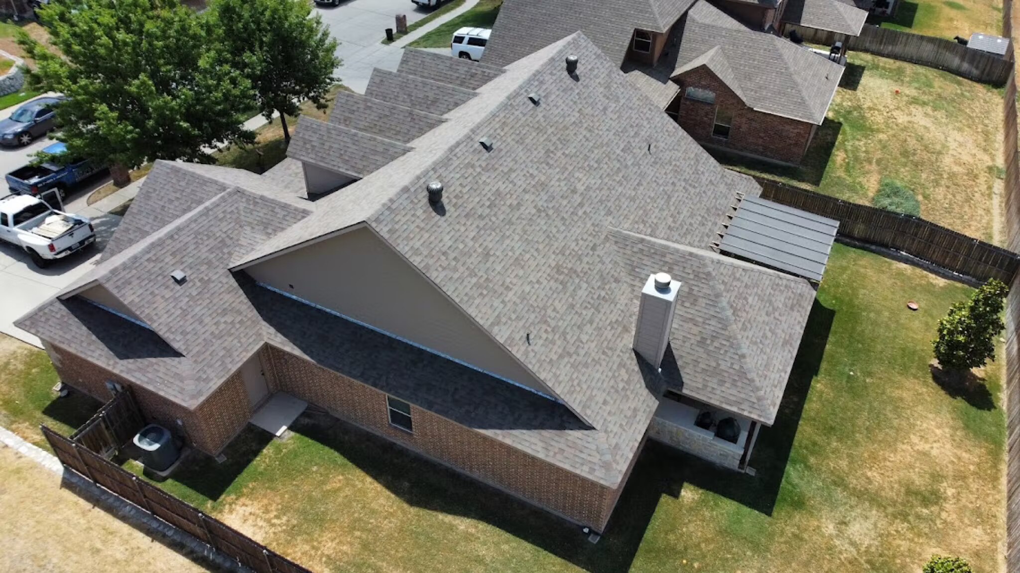 Aerial view of a well-maintained multi-gable shingle roof on a DFW home