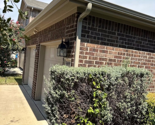 New seamless gutter and downspout running along the roofline of a brick home
