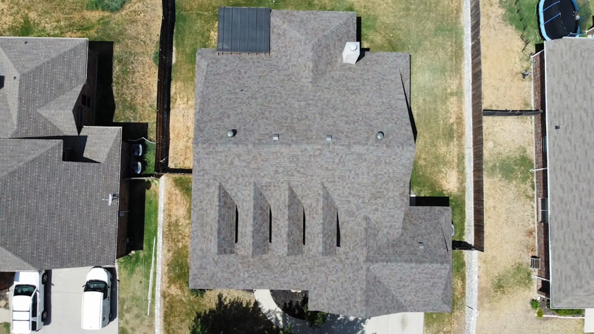 Straight-down aerial of a newly shingled roof with clean ridgelines and roof vents