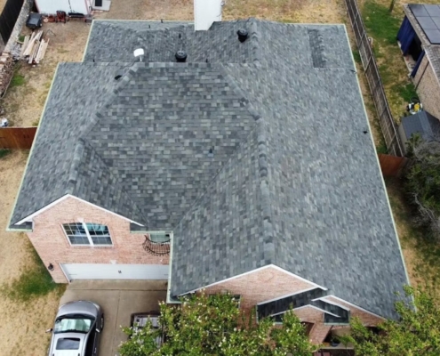 Top-down aerial of a completed slate-gray shingle roof with attic vents