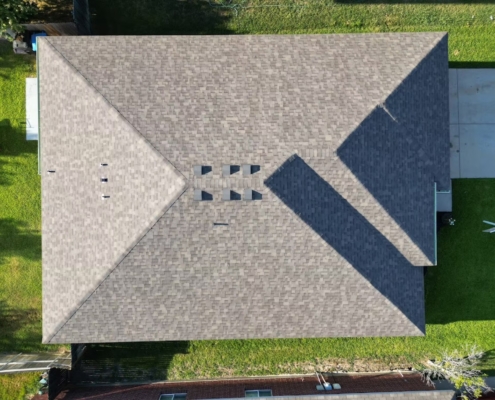 Overhead view of a finished tan shingle hip roof with turtle vents on a residential home.
