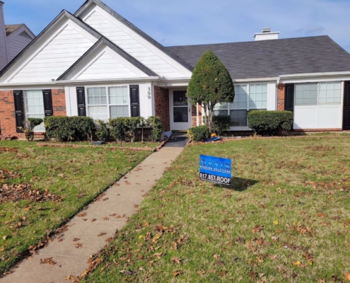Brick-and-siding ranch home showing a new shingle roof with a front walk and scattered autumn leaves.