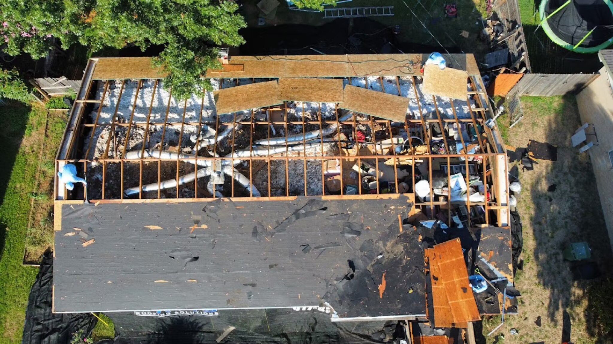 Overhead view of a roof torn down to the rafters and framing during a major rebuild