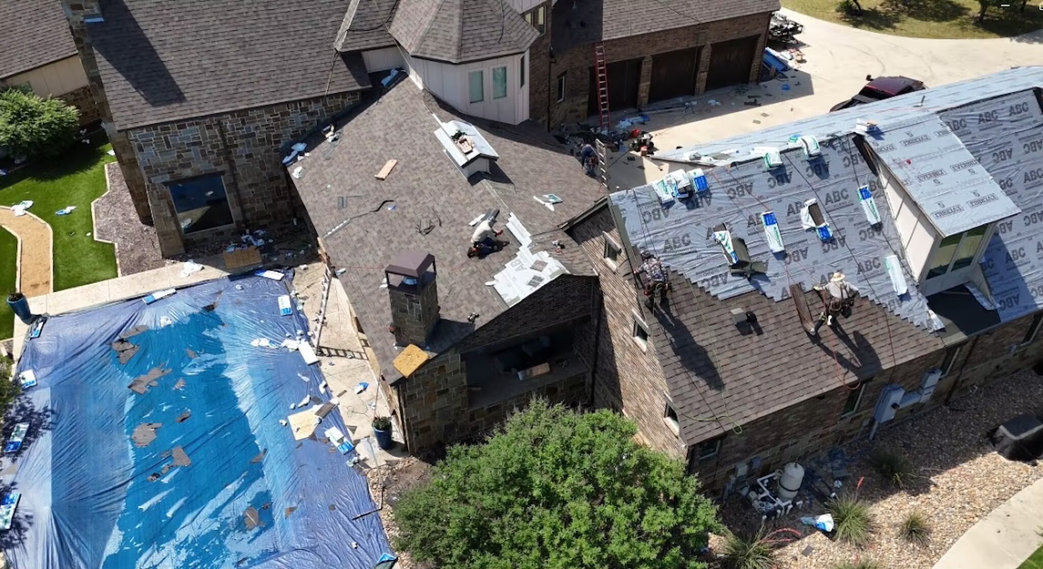 Overhead view of a roof replacement in progress with synthetic underlayment and shingle bundles staged