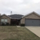 Front exterior of a single-story brick home with a new dark shingle roof on a cloudy day