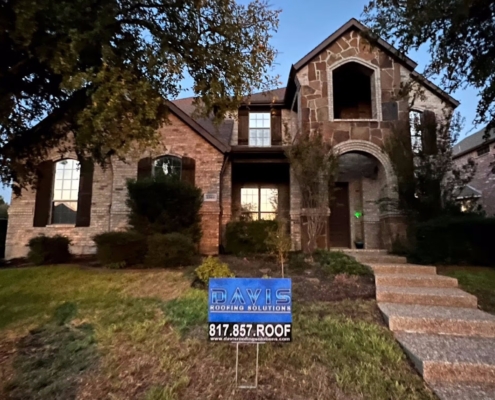 Two-story stone and brick home at dusk after a completed roof replacement