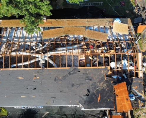 Aerial of a home stripped down to the rafters with old decking and insulation exposed
