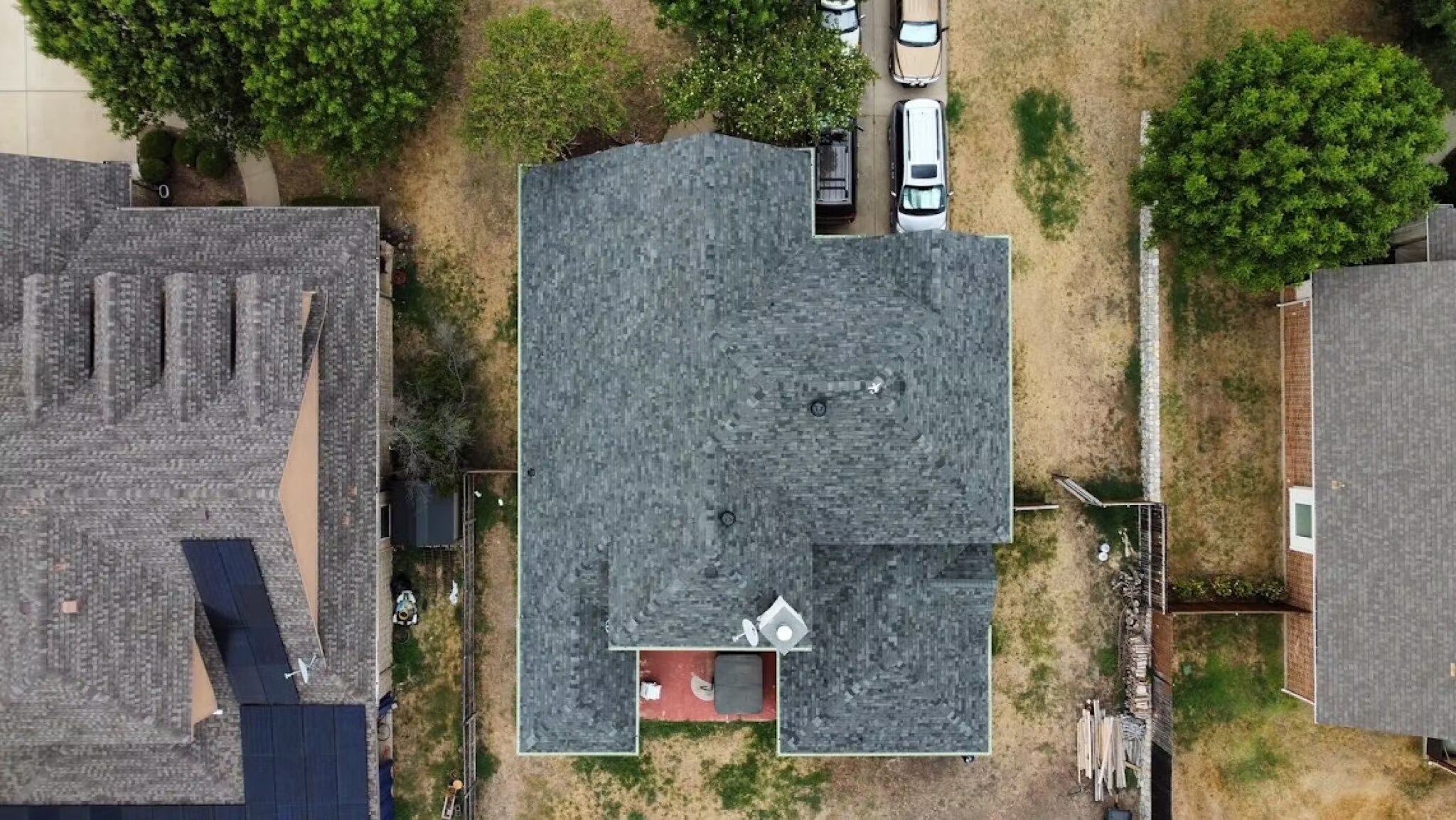 Overhead drone shot of a finished gray shingle roof on a suburban home