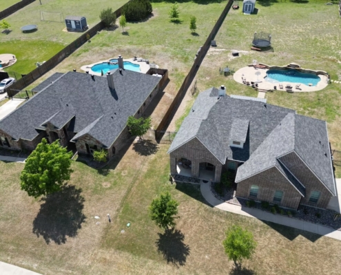 Two neighboring homes with new gray shingle roofs and backyard pools, seen from above