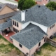 Drone view of a completed slate-gray shingle roof on a two-story brick home in DFW