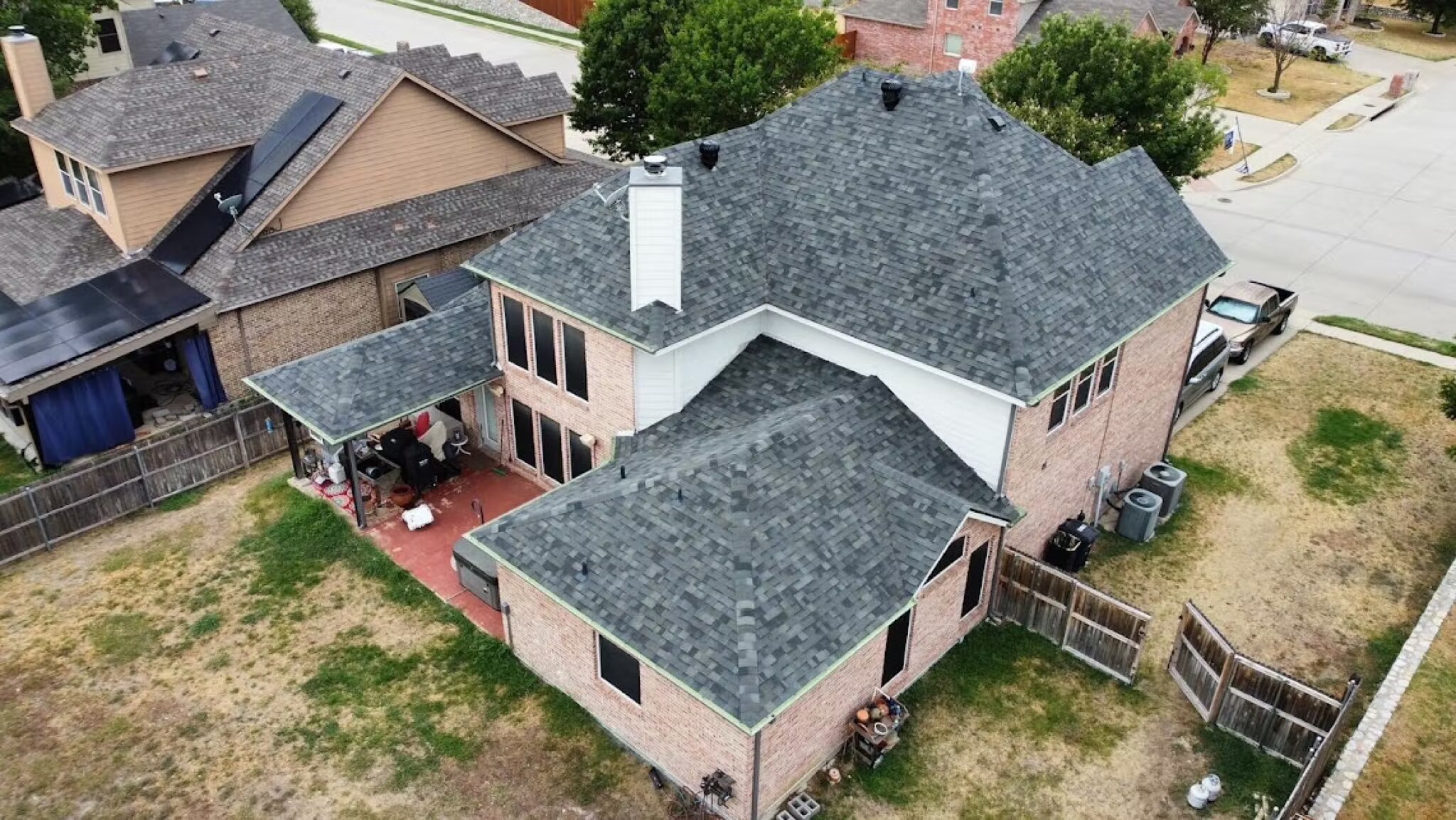 Drone view of a completed slate-gray shingle roof on a two-story brick home in DFW