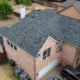 Aerial of a finished charcoal shingle roof on a two-story brick home with a chimney
