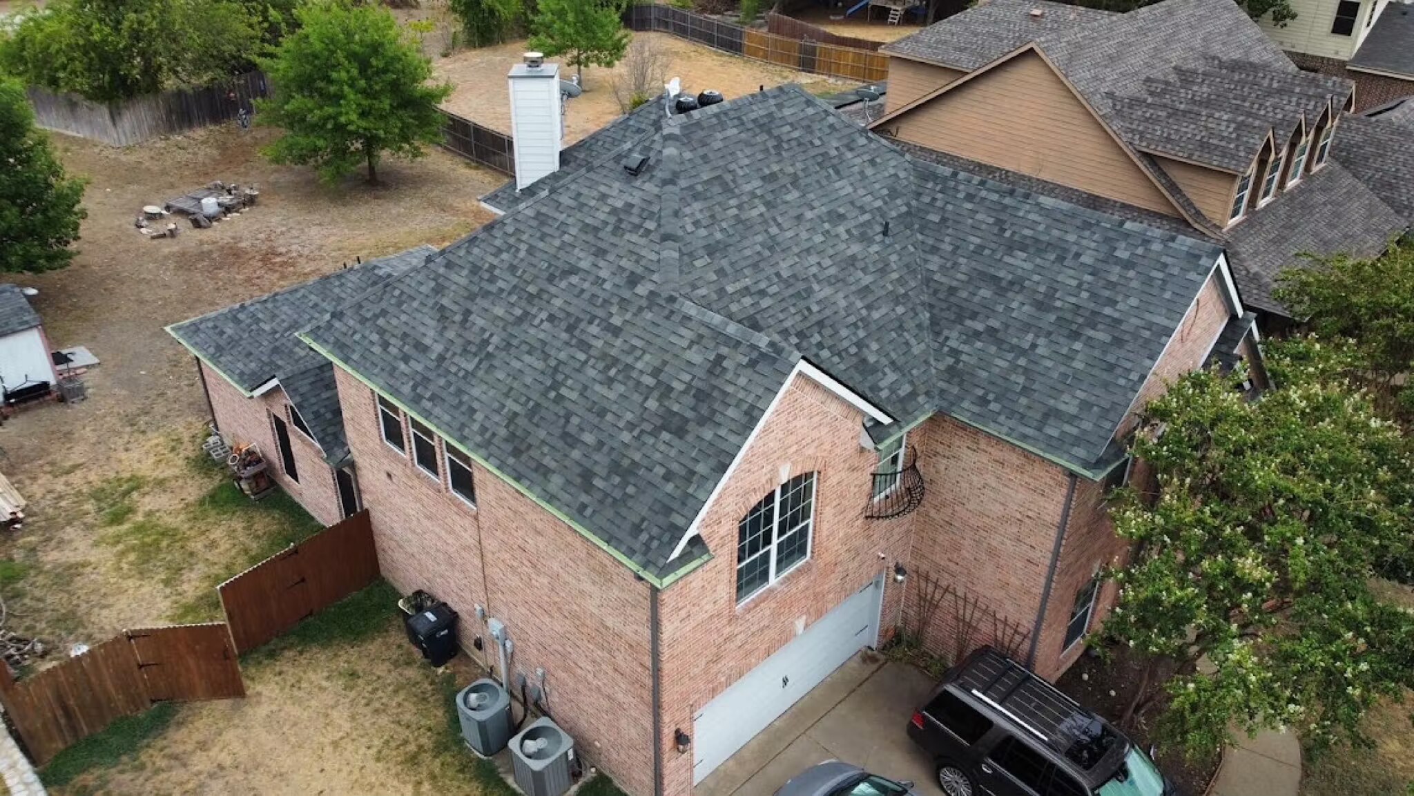 Aerial of a finished charcoal shingle roof on a two-story brick home with a chimney